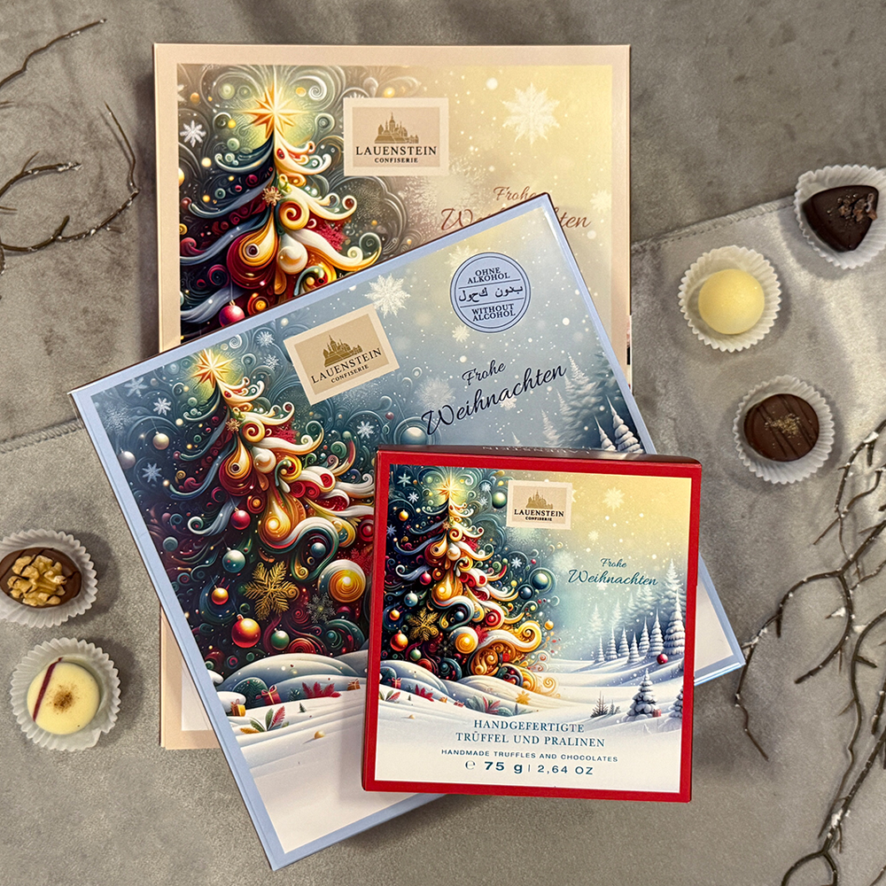 drei übereinander gelagerte, unterschiedlich große Weihnachts-Pralinenschachteln und lose Pralinen