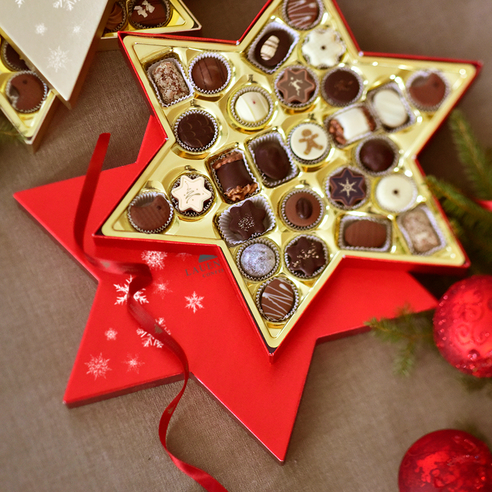 Geöffnete Lauensteiner Pralinenschachtel in Sternform inmitten weihnachtlicher Dekoration