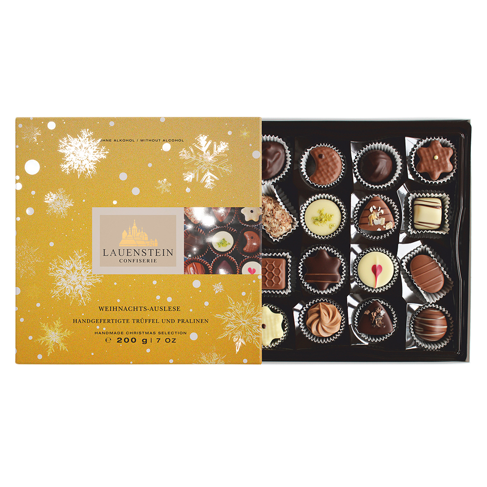 Geöffnete Lauenstein Weihnachts-Auslese Pralinenschachtel in Gold mit Schneeflocken und einer vielfältigen Auswahl handgefertigter Pralinen