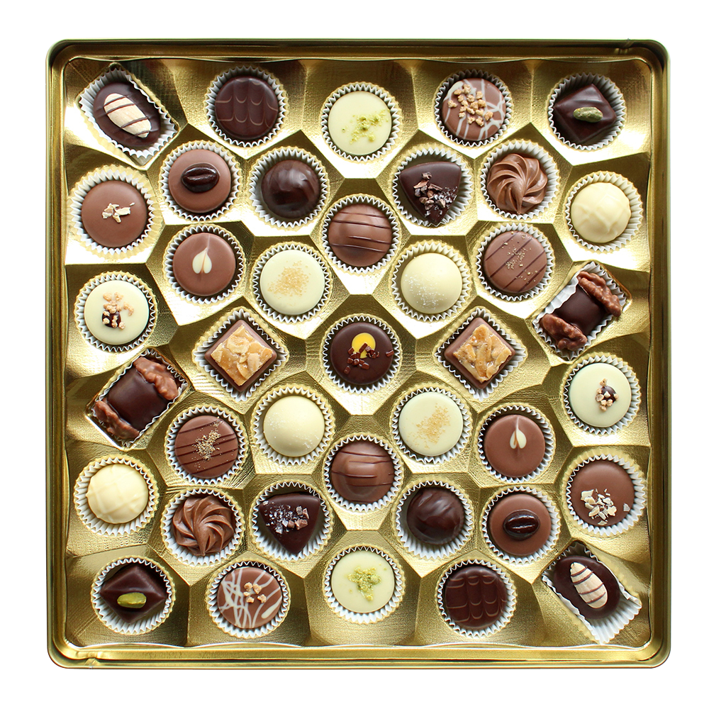 Draufsicht auf Pralinen in einer quadratischen, goldenen Einlage