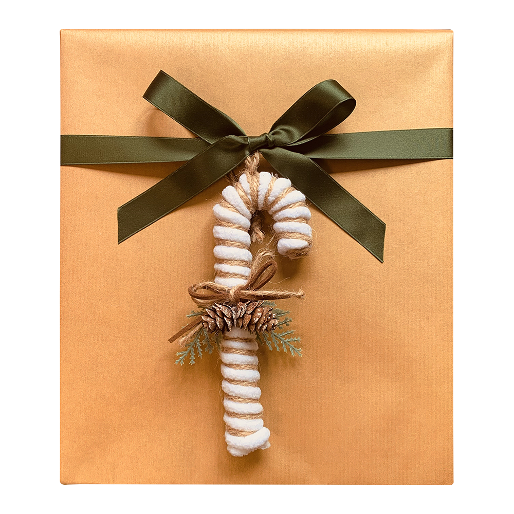 Ein goldfarben verpacktes Geschenk mit dunkelgrüner Schleife und einer dekorativen Zuckerstange in weiß gold gestreift