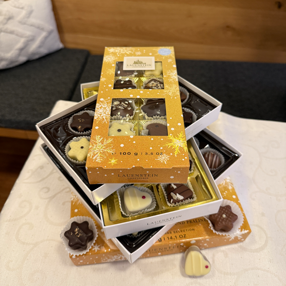 Ein Stapel verschieden großer, geöffneter Weihnachts-Auslesen mit feiner Pralinenauswahl