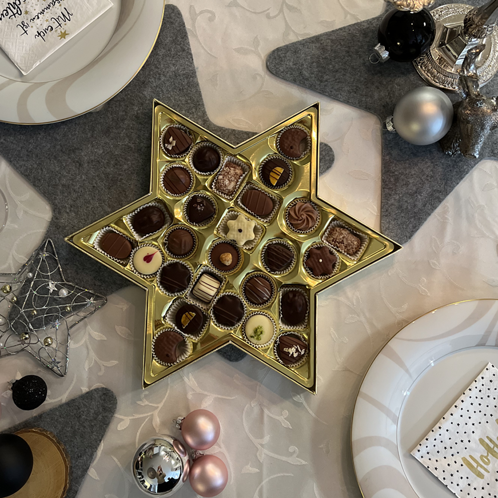 Geöffnete Pralinenschachtel auf einem weihnachtlich gedeckten Tisch