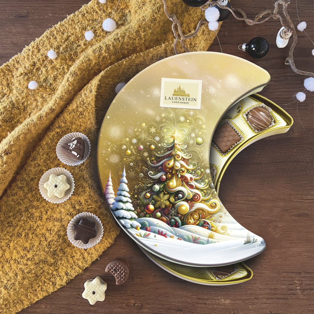Pralinendose auf Holzboden, dekoriert mit feinen Trüffeln, gelber Decke und Weihnachtsschmuck