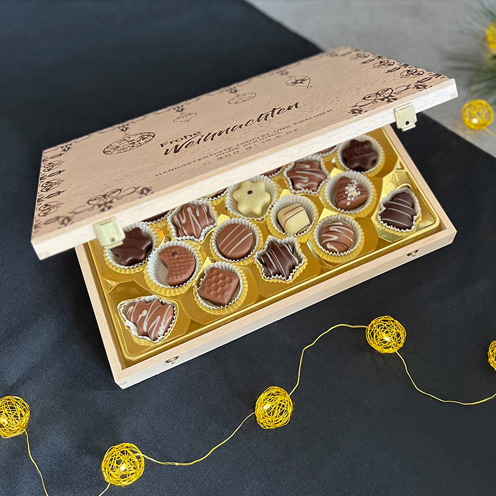 Geöffnetes Schatzkästchen mit weihnachtlichen Pralinen umgeben von einer Lichterkette