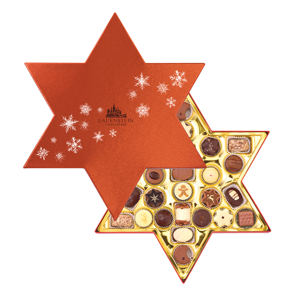 Geöffnete sternförmige Lauensteiner Pralinenmischung mit rotem Deckel und silbernen Schneeflocken mit gemischten Weihnachtspralinen