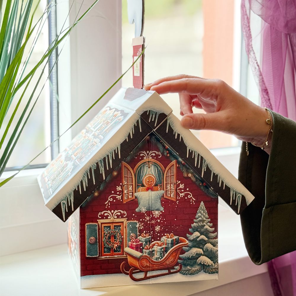 eine Hand öffnet ein Türchen im Dach des Adventskalenders