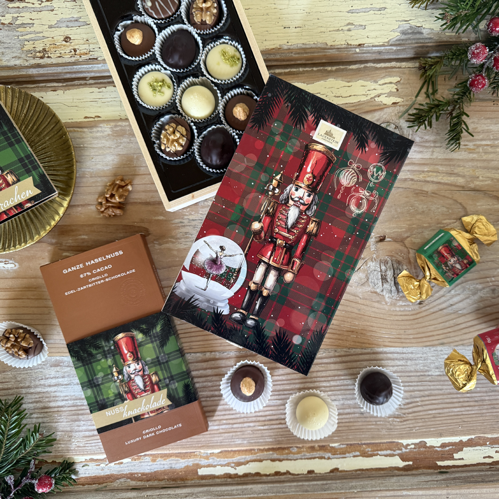Weihnachtliches Schokoladen-Arrangement von Lauenstein mit Nussknacker-Pralinenschachtel, Haselnuss-Schokolade und einzelnen Pralinen auf Holz
