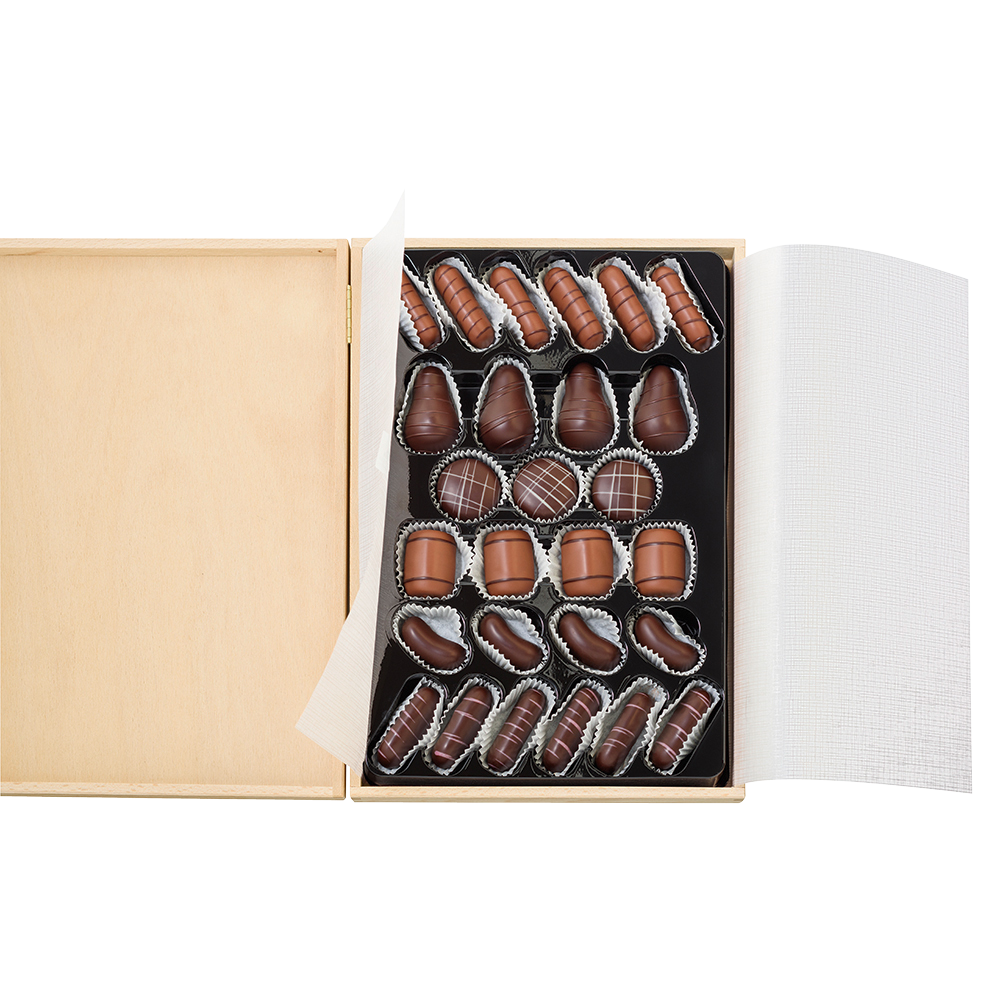 Geöffnetes Lauensteiner Holzkästchen mit weißem Pergamentpapier und 27 Pralinen