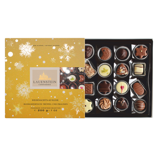 Geöffnete Lauenstein Weihnachts-Auslese Pralinenschachtel in Gold mit Schneeflocken und einer vielfältigen Auswahl handgefertigter Pralinen