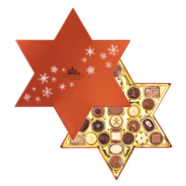 Geöffnete sternförmige Lauensteiner Pralinenmischung mit rotem Deckel und silbernen Schneeflocken mit gemischten Weihnachtspralinen
