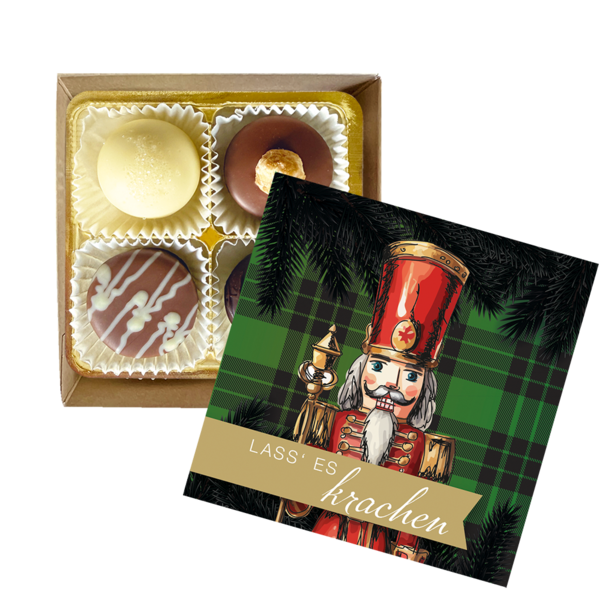 Geöffnete Pralinenschachtel mit vier unterschiedlichen Pralinen ohne Alkohol neben Deckel mit Nussknacker-Motiv und Aufschrift Lass es krachen