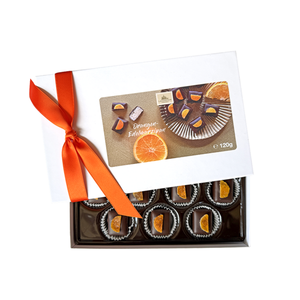 Dunkle Orangen-Edelmarzipan-Pralinen von Lauenstein in halb geöffneter, weißer Geschenkbox mit orangefarbener Schleife