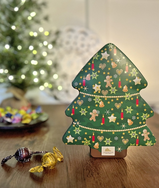 Stimmungsvoll verpackte Weihnachtsgeschenke vor leuchtendem Christbaum