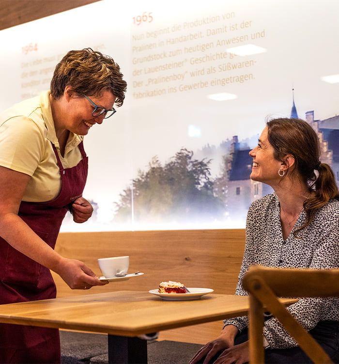 Freundliche Bedienung bringt lächelnder Frau ein Stück Kuchen