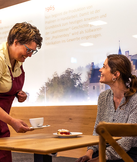 Café in der Fischbachsmühle, Bedienung bringt Frau einen Erdbeerkuchen