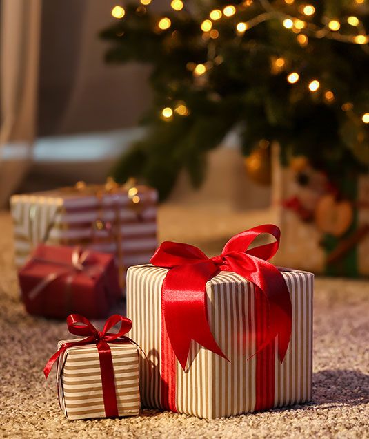 Stimmungsvoll verpackte Weihnachtsgeschenke vor leuchtendem Christbaum